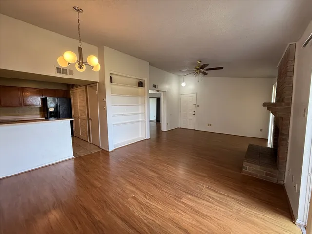 a view of a room with wooden floor and kitchen view
