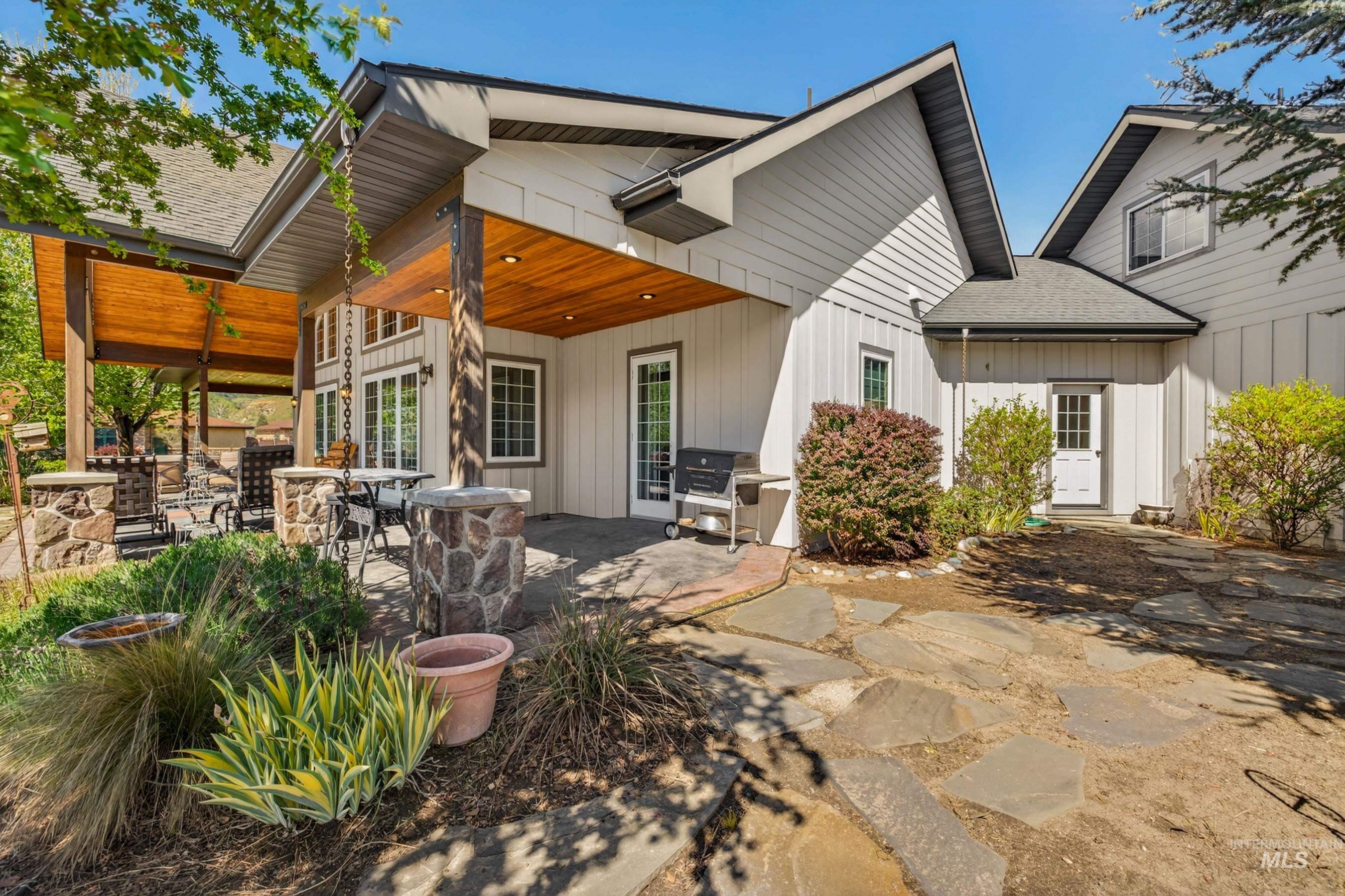 113 Deford Road White Bird, ID 83554 - Photo 35 of 49 Expansive stone patio featuring a covered outdoor living area with a wood-finish ceiling, stone-clad columns, and multiple access points to the residence