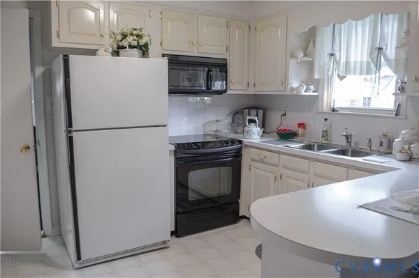 a kitchen with a refrigerator sink and white cabinets