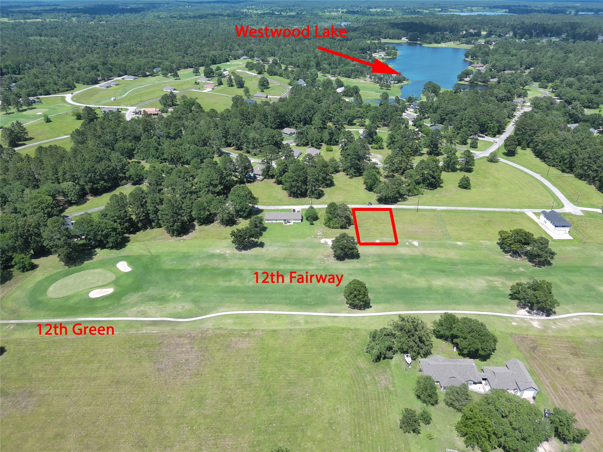 59 Oakridge South Trinity, TX 75862 - Photo 4 of 10 This aerial photo showcases a scenic residential lot adjacent to the 12th fairway and green of a golf course, with lush greenery and trees. Westwood Lake is visible in the background, providing a picturesque and serene landscape ideal for golf enthusiasts and nature lovers.