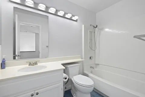 a bathroom with a granite countertop sink toilet mirror and bathtub