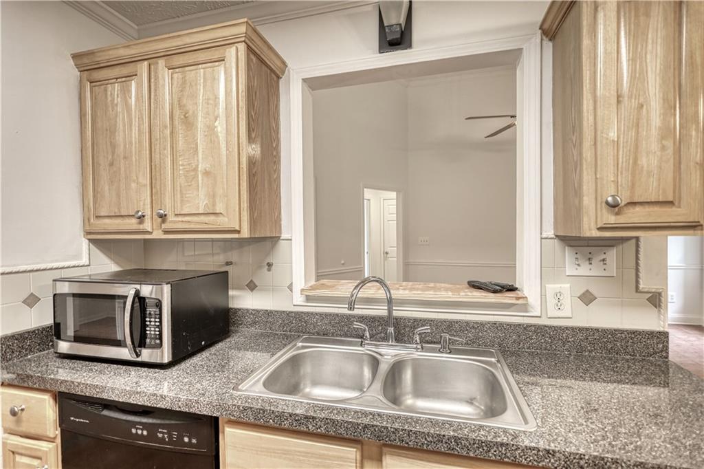 115 Huntington Street Covington, GA 30016 - Photo 18 of 77 a kitchen with granite countertop a sink a counter top space cabinets and stainless steel appliances