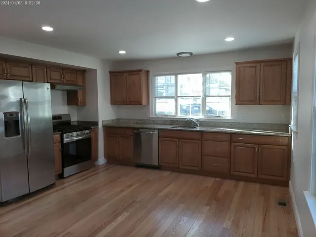 a kitchen with granite countertop a refrigerator and wooden cabinets