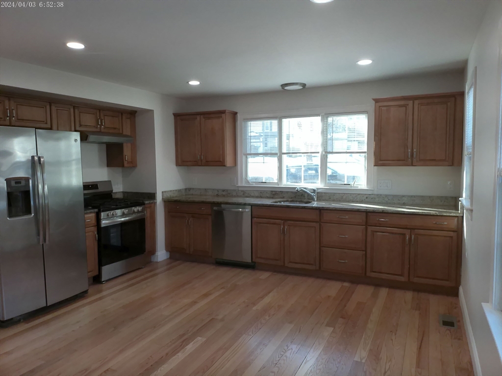 857 Washington Street, Unit 857 Canton, MA 02021 - Photo 3 of 17 a kitchen with granite countertop a refrigerator and wooden cabinets