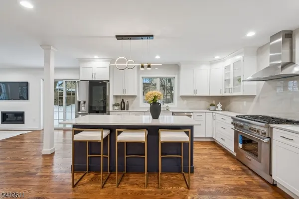 a kitchen with stainless steel appliances granite countertop a stove top oven a sink dishwasher and white cabinets with wooden floor