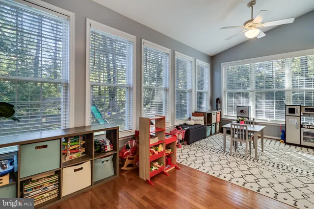 a living room with furniture large windows and wooden floor