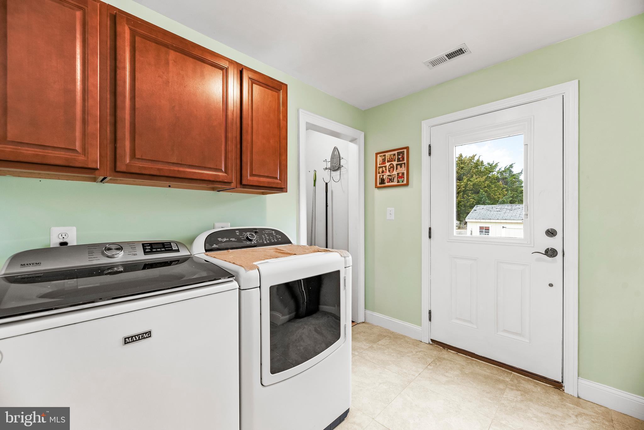 3095 Calvert Boulevard Lusby, MD 20657 - Photo 31 of 105 a utility room with stainless steel appliances granite countertop a sink a washer and dryer with wooden cabinets