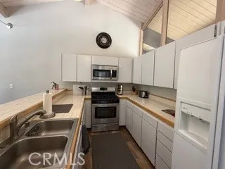 a kitchen with stainless steel appliances a sink a stove a refrigerator cabinets and furniture