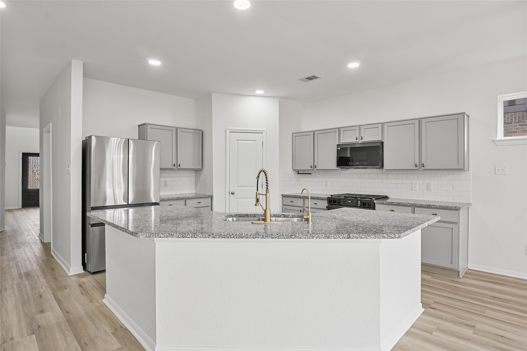 10511 Kings River Drive Rosharon, TX 77583 - Photo 9 of 25 a kitchen with stainless steel appliances granite countertop a refrigerator a stove a sink and white cabinets with wooden floor