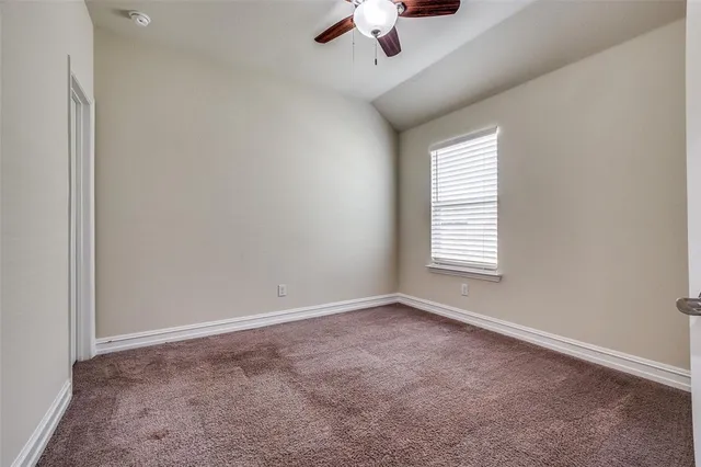an empty room with a window and ceiling fan