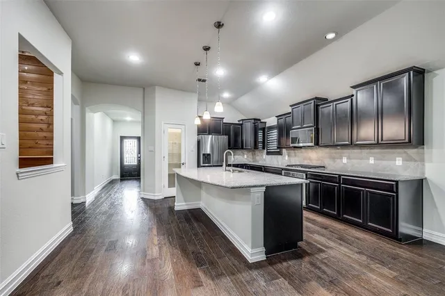 a large kitchen with stainless steel appliances lots of counter space and wooden floor