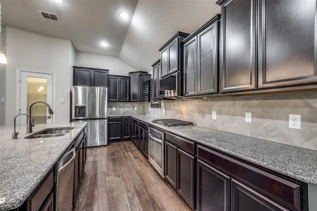 a kitchen with granite countertop stainless steel appliances cabinets a sink and a counter top space