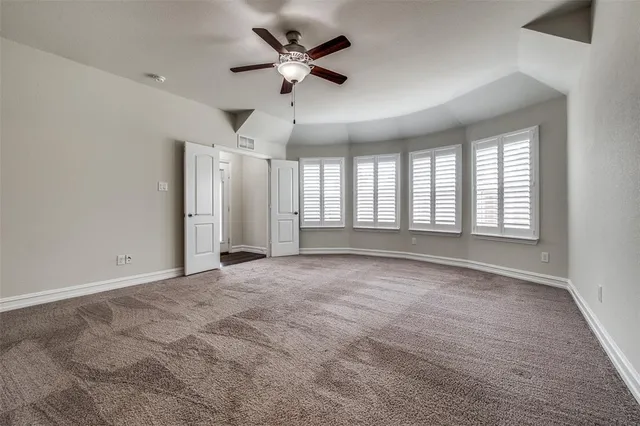 a view of an empty room with a chandelier fan and a window