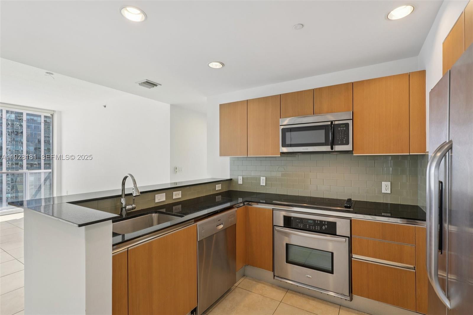1060 Brickell Avenue, Unit 2607 Miami, FL 33131 - Photo 4 of 46 a kitchen with granite countertop a sink and stainless steel appliances