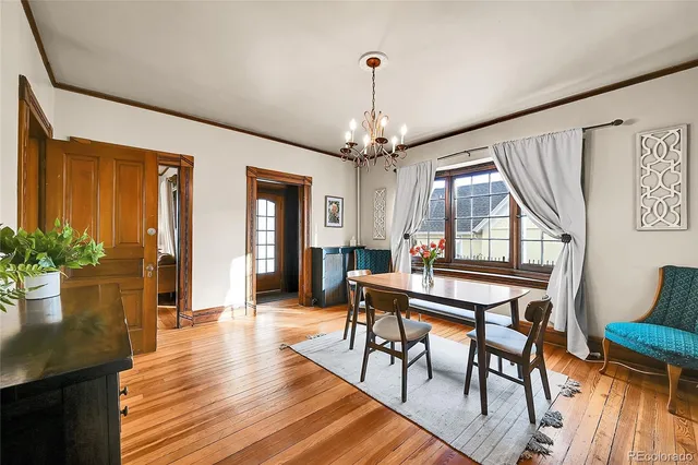a dining room with wooden floor a chandelier a wooden table and chairs