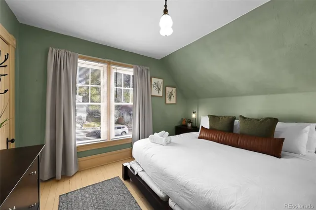 a bedroom with a bed wooden floor and window