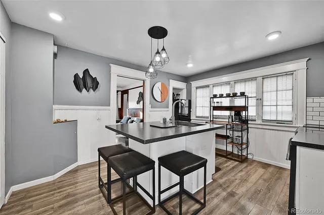 a kitchen with stainless steel appliances granite countertop a stove a sink dishwasher and a dining table with wooden floor