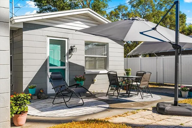 a view of a patio with table and chairs potted plants and a barbeque