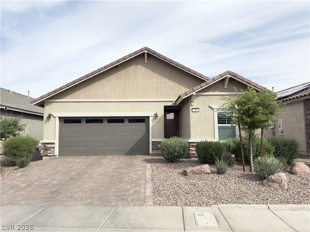 Ranch-style house featuring a garage, decorative driveway, stucco siding, and stone siding