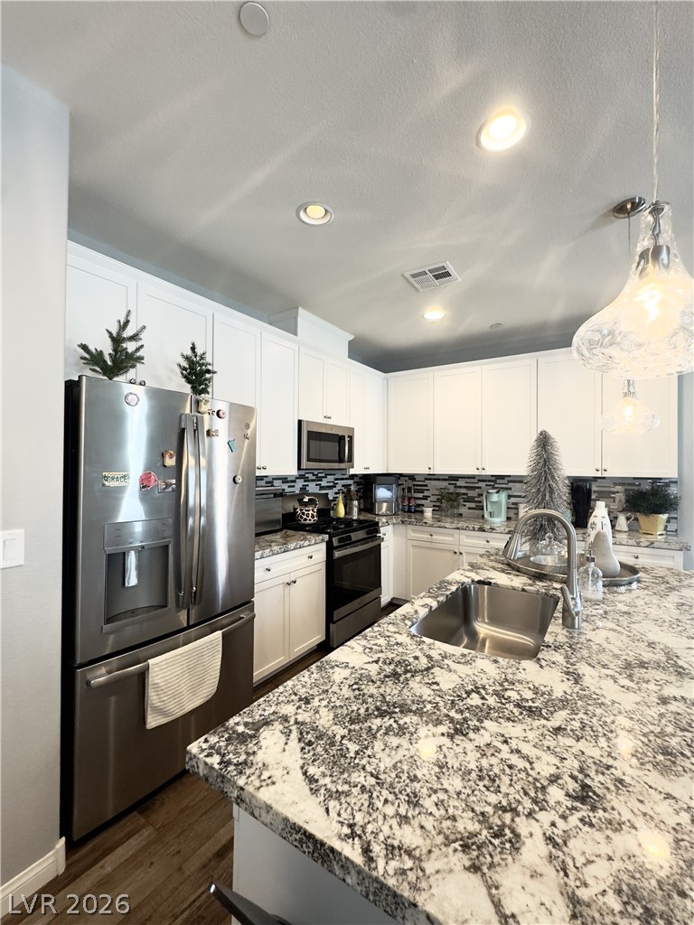 78 Summer Rhapsody Avenue Henderson, NV 89015 - Photo 10 of 31 Kitchen with stainless steel appliances, decorative light fixtures, light stone counters, white cabinets, and dark wood-style floors