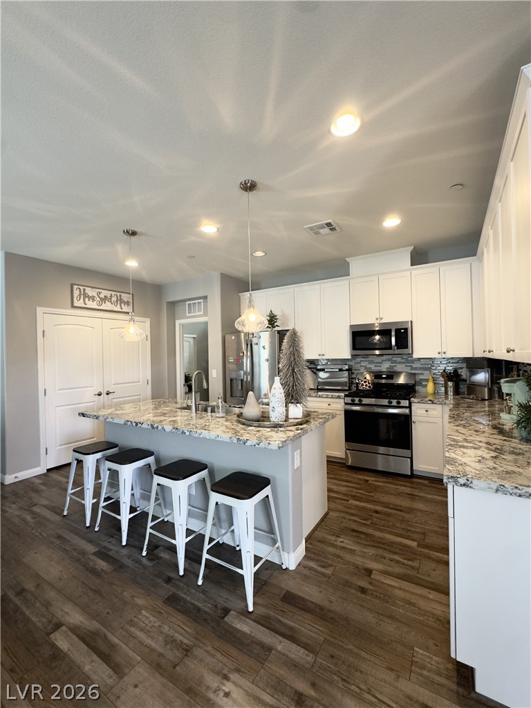 78 Summer Rhapsody Avenue Henderson, NV 89015 - Photo 11 of 31 Kitchen with a kitchen bar, light stone counters, a center island with sink, and stainless steel appliances