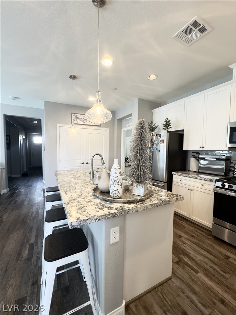 78 Summer Rhapsody Avenue Henderson, NV 89015 - Photo 12 of 31 Kitchen with a kitchen breakfast bar, stainless steel appliances, dark wood-style floors, a center island with sink, and pendant lighting