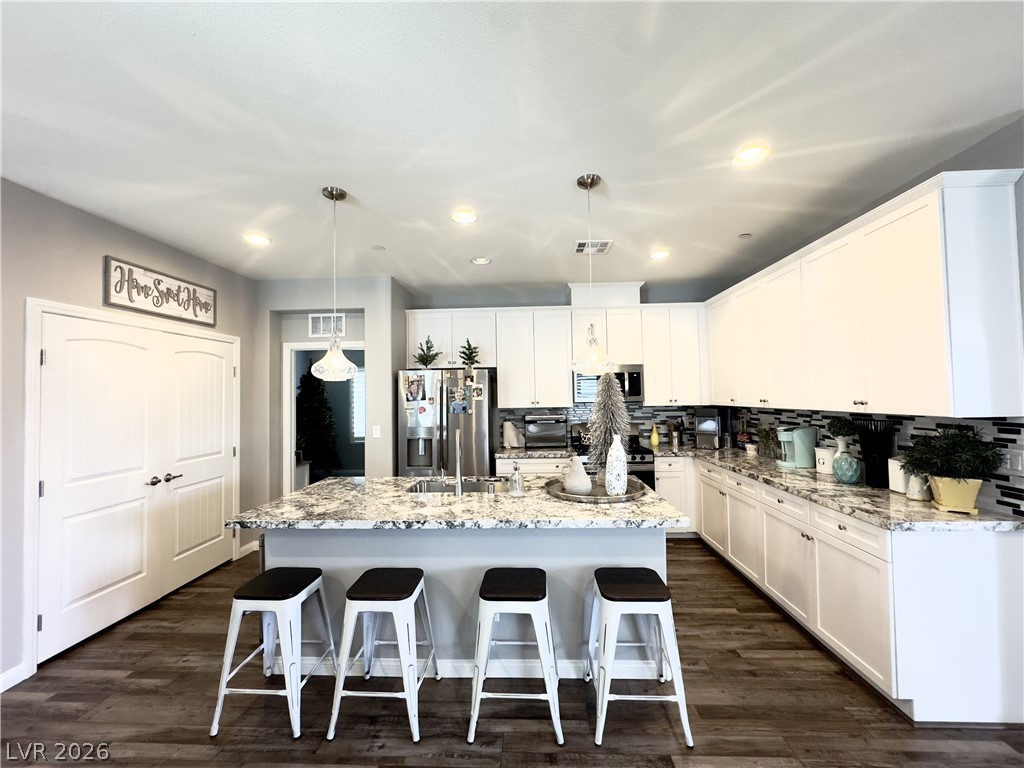 78 Summer Rhapsody Avenue Henderson, NV 89015 - Photo 3 of 31 Kitchen featuring white cabinets, stainless steel appliances, a breakfast bar area, and pendant lighting