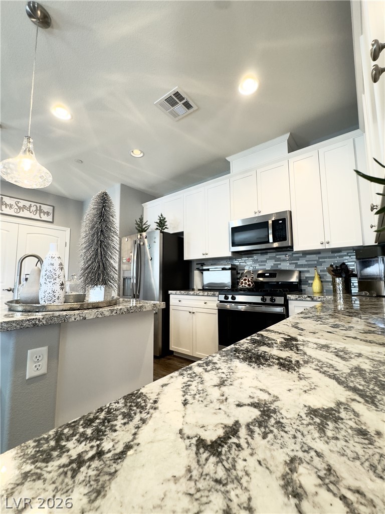 78 Summer Rhapsody Avenue Henderson, NV 89015 - Photo 5 of 31 Kitchen featuring light stone counters, stainless steel appliances, decorative light fixtures, white cabinetry, and decorative backsplash
