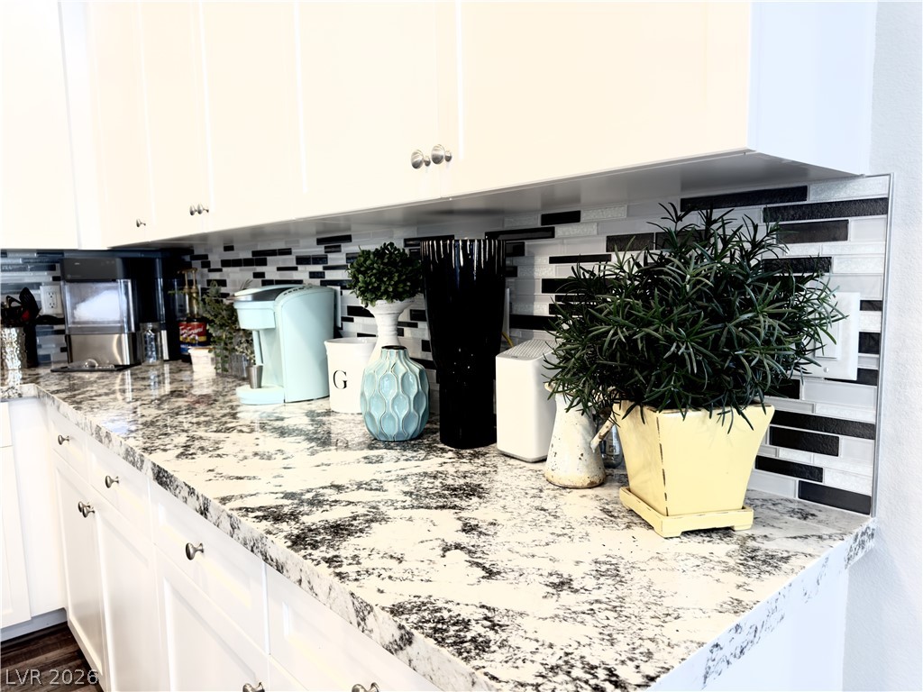 78 Summer Rhapsody Avenue Henderson, NV 89015 - Photo 6 of 31 Kitchen with backsplash, white cabinets, and light stone countertops