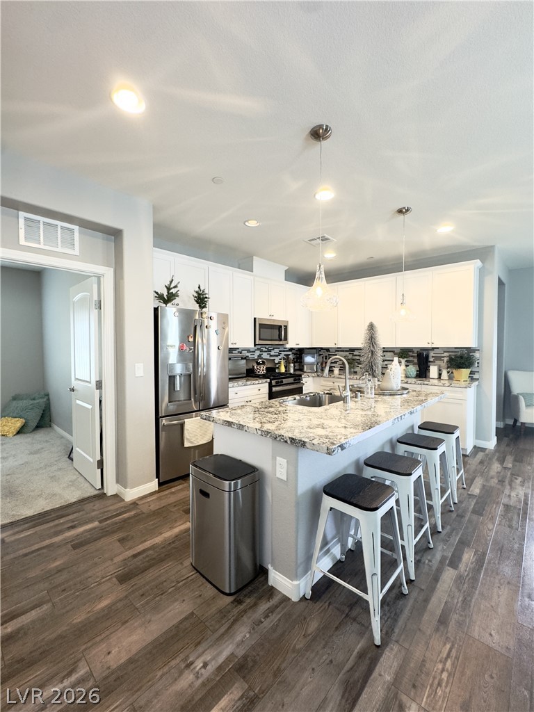 78 Summer Rhapsody Avenue Henderson, NV 89015 - Photo 7 of 31 Kitchen featuring stainless steel appliances, white cabinets, light stone counters, backsplash, and decorative light fixtures