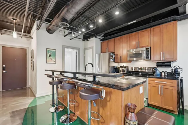 a kitchen with stainless steel appliances granite countertop a sink a stove and cabinets