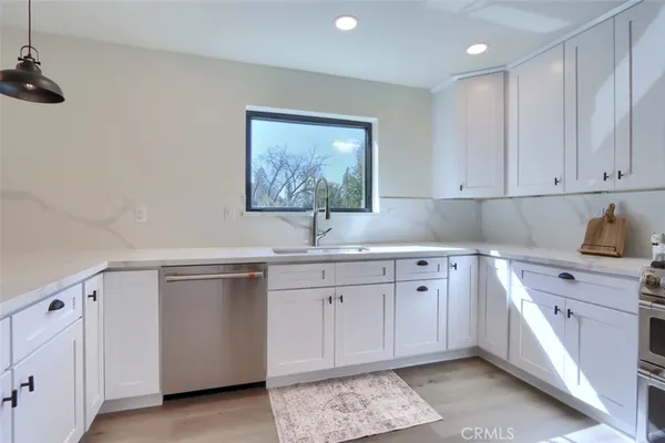 a kitchen with white cabinets sink and white stainless steel appliances