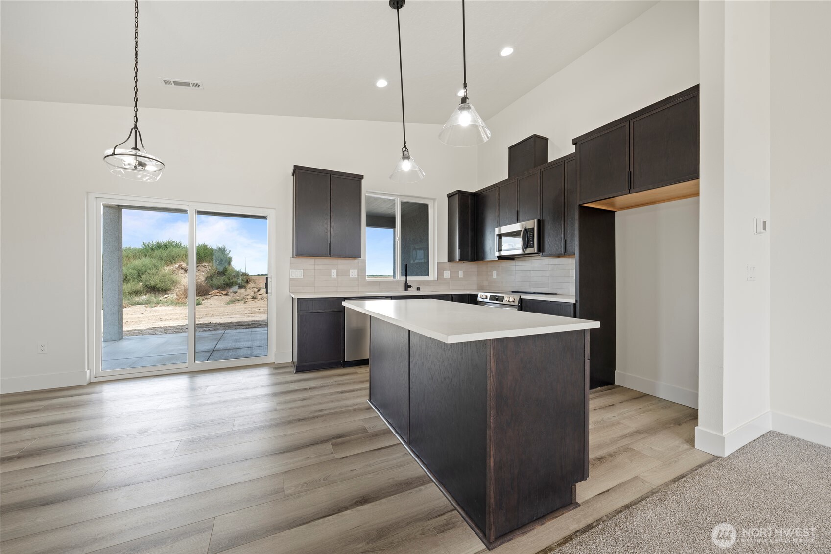 1101 E Mount Othello, WA 99344 - Photo 18 of 34 a large kitchen with stainless steel appliances kitchen island a large counter top a sink a refrigerator and a wooden floor