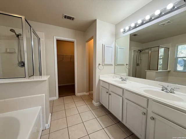 a spacious bathroom with a double vanity sink mirror and shower