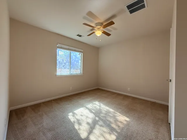 an empty room with windows and fan