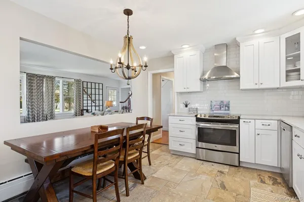 a kitchen with stainless steel appliances kitchen island granite countertop a stove a sink a dining table and chairs