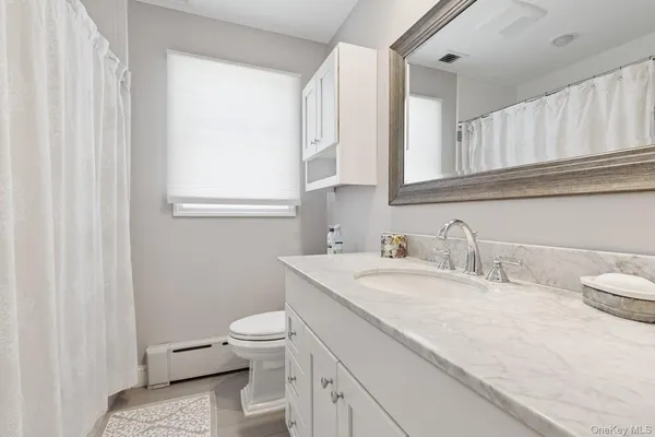 a bathroom with a granite countertop sink a toilet and a mirror
