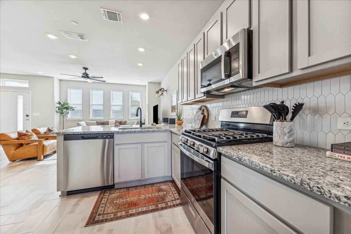9015 Cattle Baron Path, Unit 1002 Austin, TX 78747 - Photo 7 of 21 a kitchen with stainless steel appliances granite countertop a stove and a sink