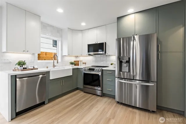 a kitchen with stainless steel appliances a stove a sink a refrigerator and a microwave
