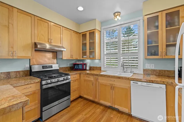 a kitchen with granite countertop stainless steel appliances a stove sink and cabinets
