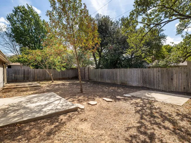 a view of a backyard with wooden fence and a large tree