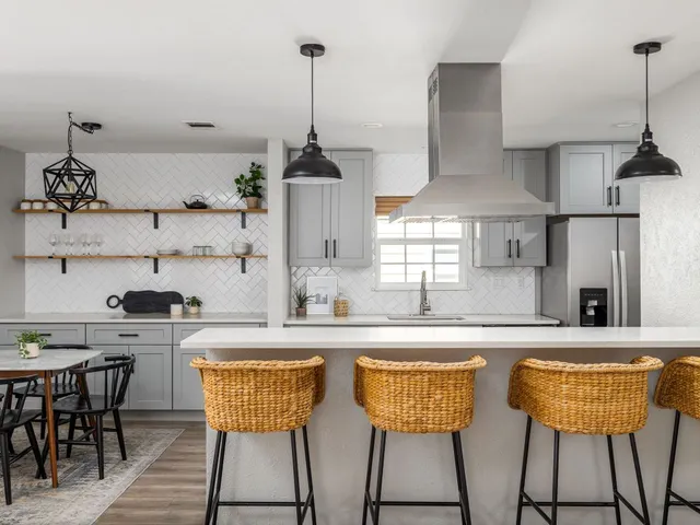 a kitchen with stainless steel appliances granite countertop a sink a stove and chairs