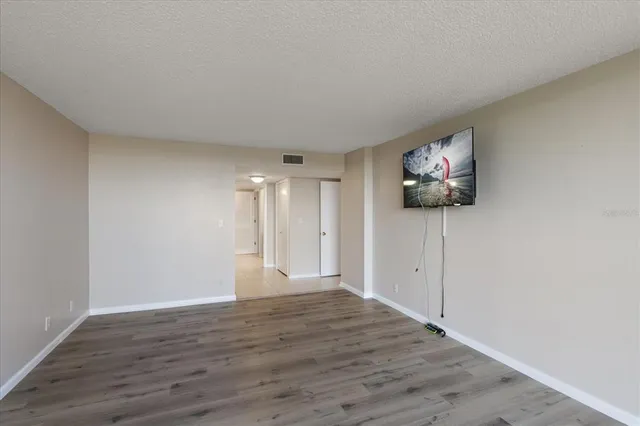 a view of empty room with wooden floor and fan
