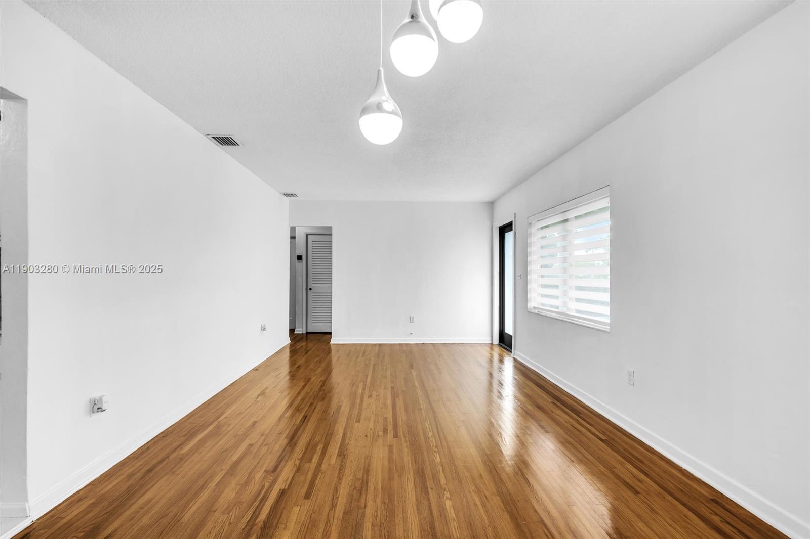 175 West 56th Street Hialeah, FL 33012 - Photo 6 of 39 a view of an empty room with wooden floor and a window