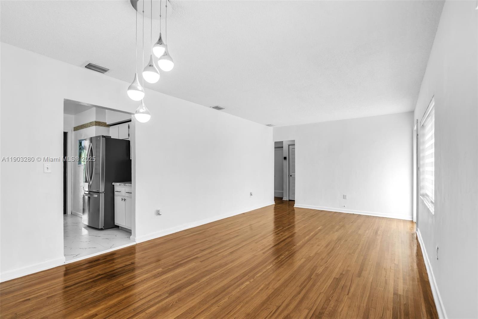 175 West 56th Street Hialeah, FL 33012 - Photo 7 of 39 an empty room with wooden floor and windows