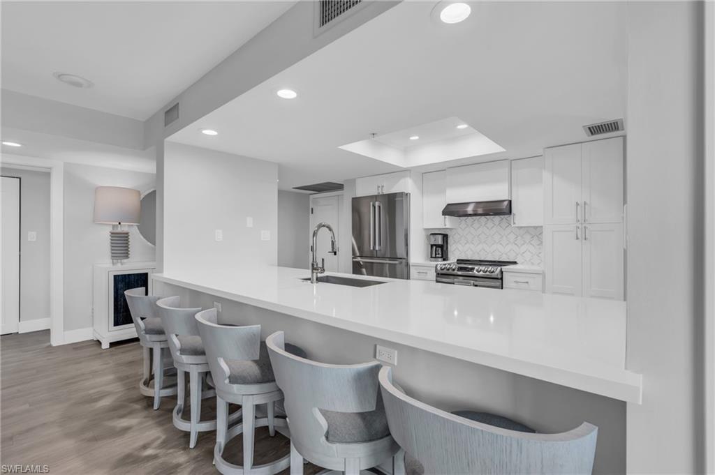 6573 Marissa Loop, Unit 1403 Naples, FL 34108 - Photo 11 of 29 a kitchen with stainless steel appliances a sink a stove a refrigerator and cabinets