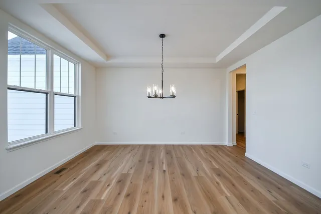 a view of a room with wooden floor chandelier and windows