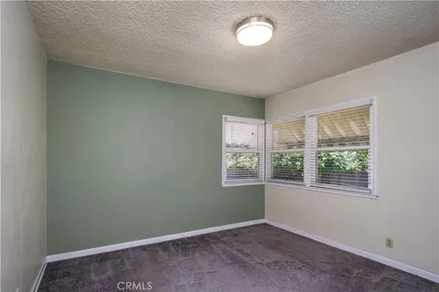 an empty room with chandelier fan and windows