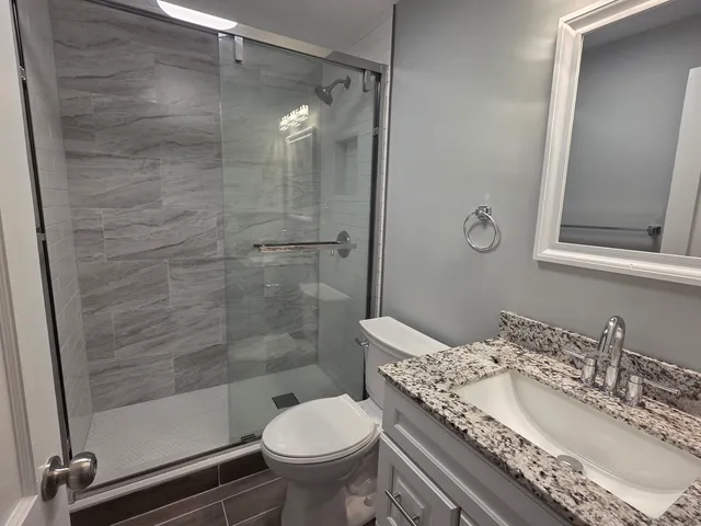 a bathroom with a granite countertop sink toilet and shower