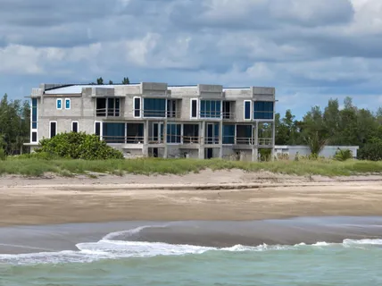 a front view of a house with a garden and trees